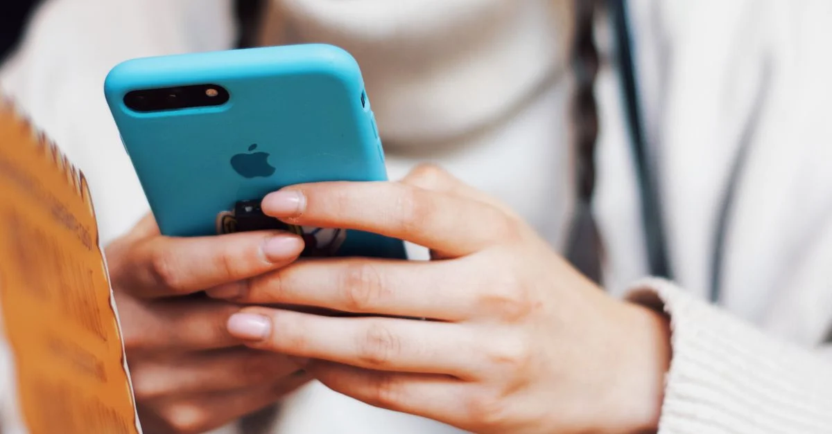 Une personne envoyant des messages sur un smartphone avec une coque bleue à l'intérieur.