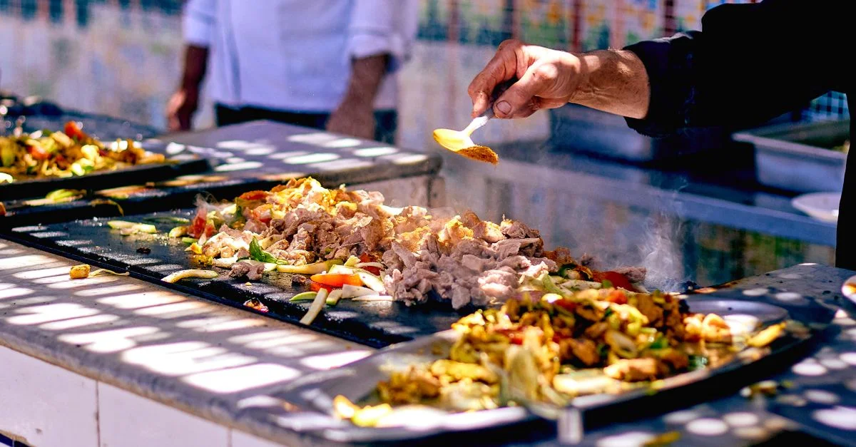 Le chef ajoute des épices à de la viande et des légumes qui grésillent dans un stand de nourriture de rue vibrant.