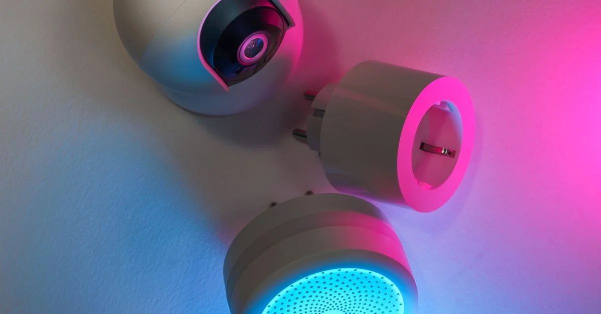 Trois appareils de maison intelligente illuminés par des lumières néon bleues et roses, mettant en valeur l'innovation technologique.