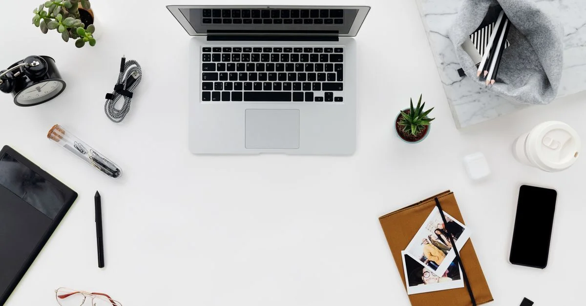Vue de dessus d'un espace de travail minimaliste avec un ordinateur portable, des gadgets et des fournitures de bureau sur un bureau propre.