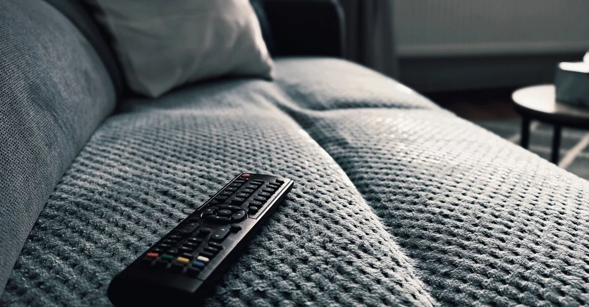 Un gros plan d'une télécommande sur un canapé texturé dans un cadre de salon douillet.