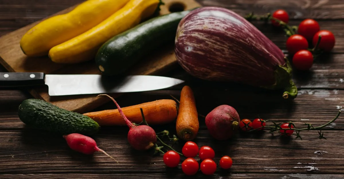 Un assortiment vibrant de légumes frais, y compris des courgettes, des aubergines et des tomates sur une planche en bois.
